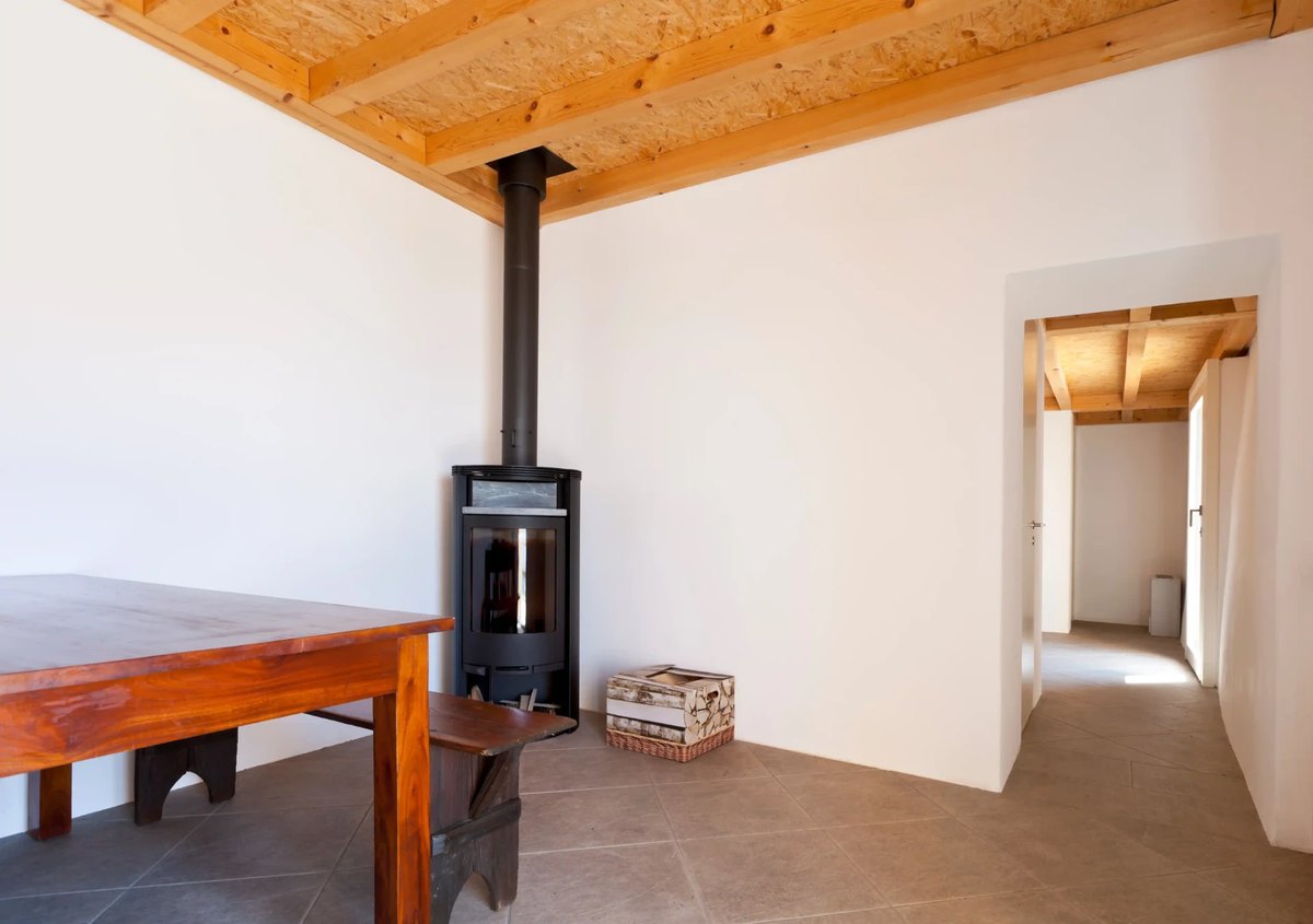 Wood stove installed in a corner hearth with wall and floor clearances visible