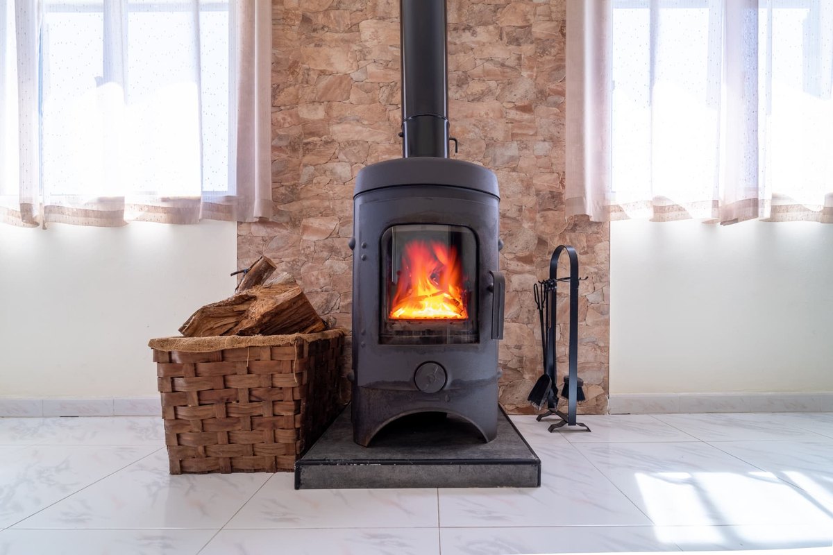 Wood stove on a hearth pad against a stone wall showing floor and wall protection